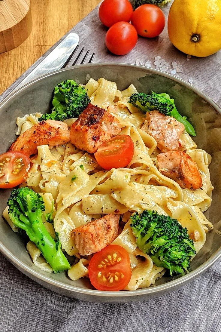 Cremige Pasta mit Lachs, Brokkoli und Tomaten auf einem Teller