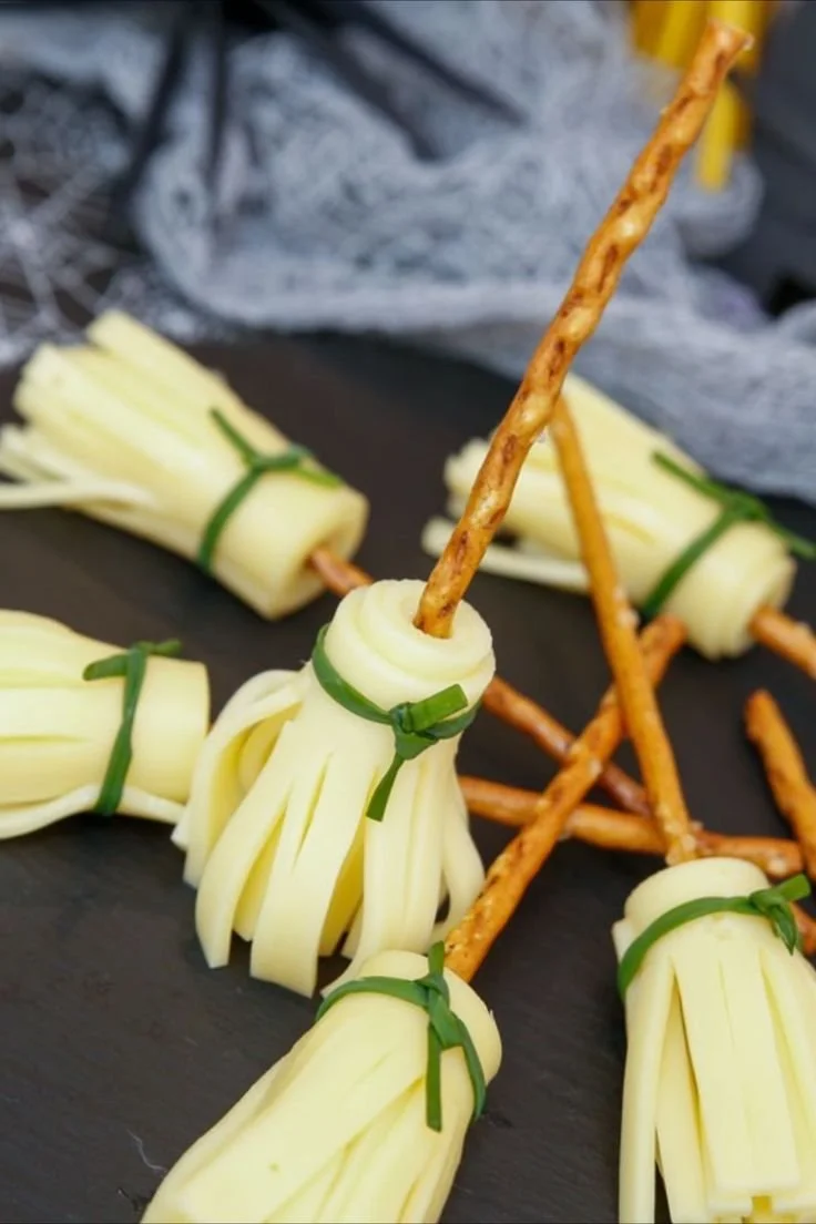 Halloween Snack Hexenbesen mit Käse und Salzstangen auf einem Tisch dekoriert