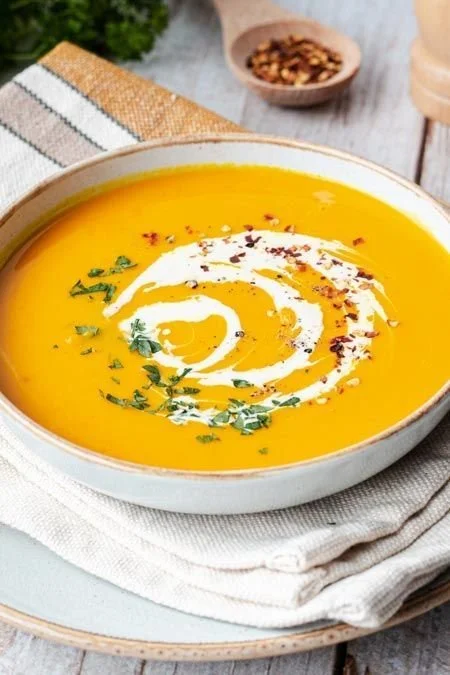 Schüssel mit dampfender Kürbissuppe in der Herbstküche