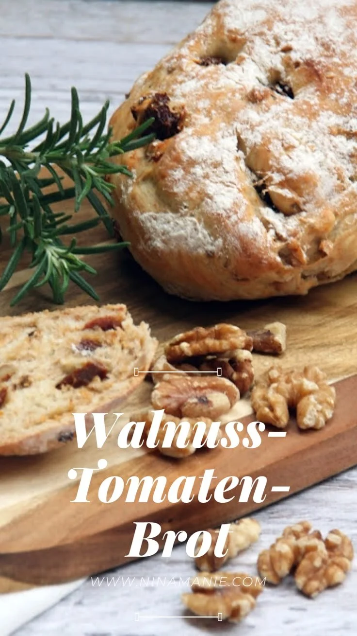 Walnuss-Tomaten-Brot auf einem Holzbrett mit frischen Kräutern.